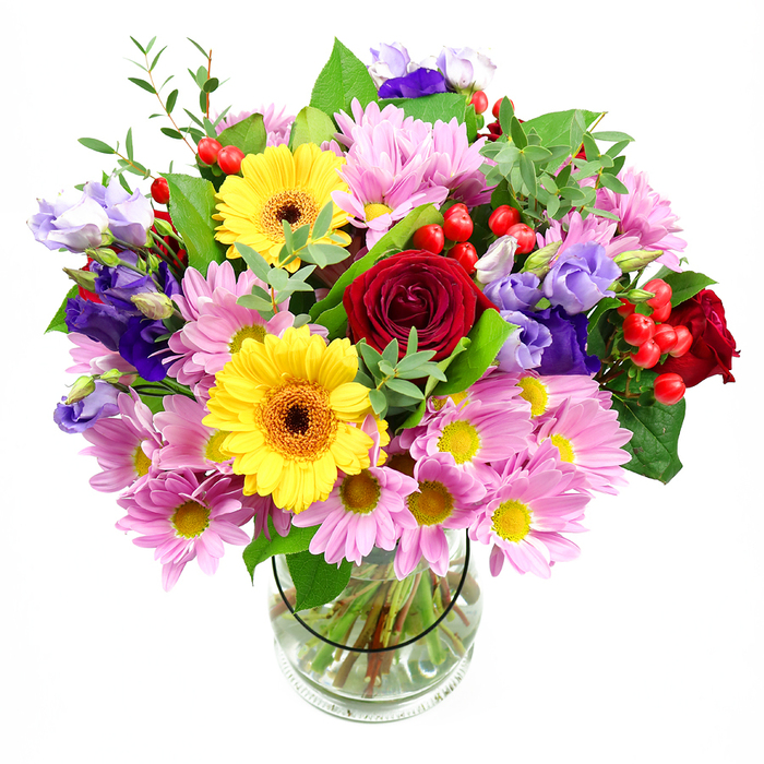 A bold and joyful mixed bouquet is shown standing in a clear glass vase against a pure white studio background, making the vivid colours and varied shapes of the flowers the main focus. At the centre, lush deep red roses bloom in full, with velvety petals spiralling outward to create a sense of depth and passion. Nearby, two striking yellow gerbera daisies with dark brown-orange centres act like radiant suns, bringing energy and optimism to the whole composition. Spreading outward from this core, clusters of soft pink and lilac chrysanthemums or daisy-like blooms fill the space, their numerous fine petals and small yellow eyes building a cushiony texture that softens the bolder colours. Rising through and above these softer blooms, stems of purple and lavender lisianthus add taller lines and elegant bell-shaped flowers, introducing a cool, refined note that balances the warmth of the reds and yellows. Bright red hypericum berries nestle here and there, their smooth round shapes catching the light and giving a playful, contemporary twist. Various types of greenery weave through the flowers: broad, deep green leaves ground the arrangement, while slender, brighter green sprigs and possibly eucalyptus tips add lightness, movement, and a just-picked freshness, much like foliage you might find on a walk from Fortis Green towards Muswell Hill Broadway. Through the clear glass vase, you can see the carefully cut stems gathered in a tidy spiral, held in clean water, demonstrating the thoughtful artistry of Fortis Green Flowers. The finished bouquet feels celebratory and welcoming, ideal for marking a birthday, a new home in N2, or simply enlivening a dining table with a burst of colour and life.