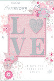 This close-up of an anniversary card reveals a design that feels as intimate and carefully composed as a bespoke bouquet delivered across Fortis Green and nearby Muswell Hill. The central focus is the word 'LOVE,' written in tall, elegant capitals that stand slightly proud of the card's surface. Each letter is coated with a fine glitter that glimmers in blush pink and silver, creating a frosted, tactile finish that catches the light like tiny crystals on rose petals. The background is awash in a gentle blush pink that gradually lightens toward creamy white and hints of silver-grey, forming a calm, radiant backdrop reminiscent of soft evening light over local garden squares. Around the word, a halo of stylized flowers and flowing vines sweeps outward, drawn in delicate, continuous lines. The flowers themselves are shaded in pale pinks, mauves, and pearly whites, with slender stems and leaves that curl and loop gracefully, much like trailing foliage arranged by an experienced florist. Scattered among them are dainty details-tiny petals, swirling tendrils, and small butterfly shapes-that add a sense of movement and quiet celebration. Subtle silver highlights trace some of the contours, echoing the glint of fine florist wire or satin ribbon in a hand-tied anniversary arrangement. In a refined, cursive script, heartfelt anniversary messages appear around and below the floral design, conveying love, gratitude, and commitment without overpowering the artwork. The composition feels spacious yet complete, like a bouquet with just the right amount of greenery, allowing the central sentiment to shine. Overall, the card suggests a gentle, enduring romance, thoughtfully captured on paper for a couple marking another year together in Fortis Green.